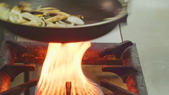 Champignon mushrooms are being stirred in a frying pan on a stove. The action takes place in a cozy kitchen, creating a delicious dish. Close-up shot of sliced white button mushrooms 