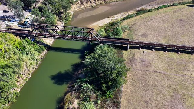 Aerial video panning around the Paterson railway bridge crossing the Hunter River in New South Wales Australia. Drone footage captures the historic rail bridge, surrounding river