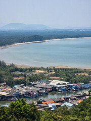 Fototapeta premium Scenic coastal village landscape view showing peaceful ocean bay fishing boats moored at calm harbor under clear sky with distant misty mountain backdrop creating serene tranquil atmosphere