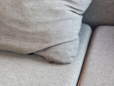 Close up view of comfortable gray fabric couch with soft cushion and pillow showing detailed texture and upholstery bringing peaceful relaxing cozy feeling to modern domestic home furniture