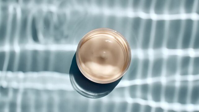 Jar of white cream and reflections sunlight in slow motion. Drop shadow effect with wave refraction of light. Sun and shadows. Layout for advertising goods, cosmetic products. Swimming pool ripples. 