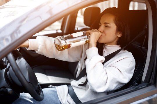 Drinking at the wheel. A drunk woman drives a car. Life threatening to drink alcohol and drive a car.