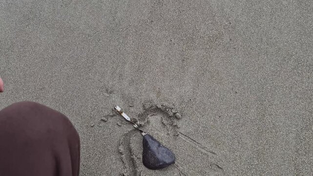 Heart sand beach person draws a heart shape around a stone on the shore expressing love and creativity