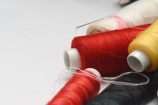 Sewing thread and needles flat lay on white background with copy space