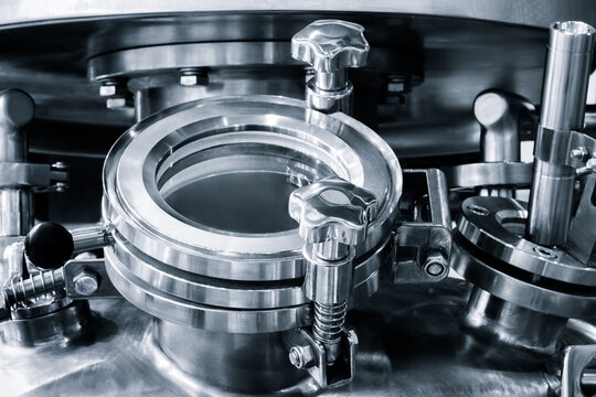 Metallic viewport features a transparent center. Round metal knobs secure the frame tightly. Stainless steel bolts reinforce the structure. Industrial machinery requires this precision
