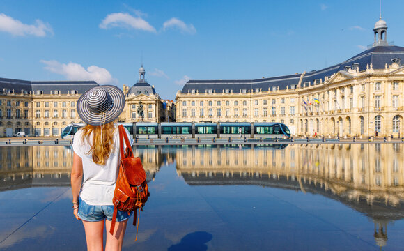 tourist woman looking at place de la bourse and water mirror with tramway in bordeaux france