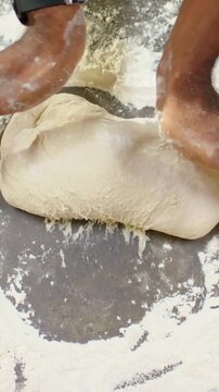 Vertical video: Pressing flour-dusted hands shaping dough at bakery counter, showing wristwatch