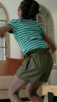 Vertical video: Stepping child in green shirt dancing at home, adult entering guiding near speaker