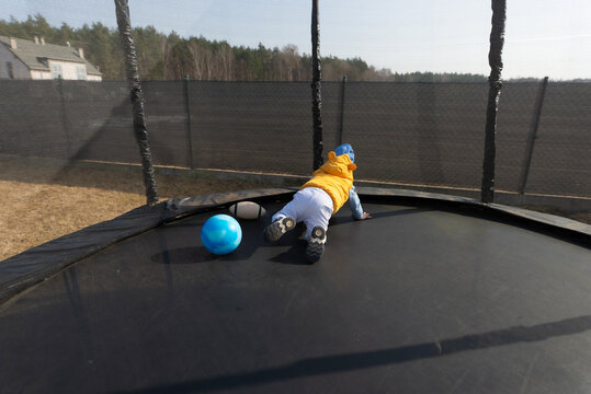 Toddler boy playing with ball on a trampoline outdoor