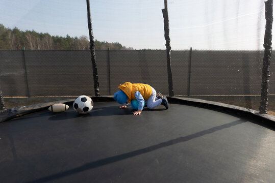 Toddler boy playing with ball on outdoor trampoline