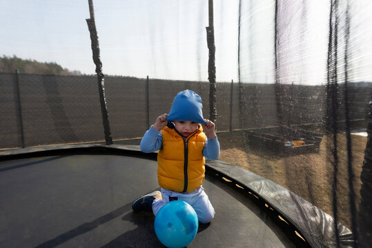 Toddler boy playing with ball on outdoor trampoline