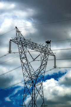 View of a high-voltage electricity pylon with a stork's nest on top against a dramatic cloudy sky Portugal.