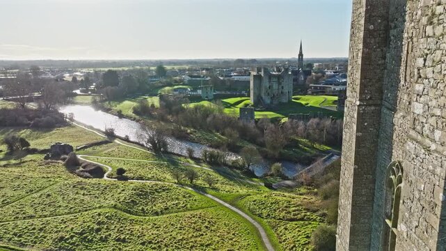 Aerial Trim Castle and the historic town of Trim on a bright sunny day, surrounded by lush greenery and the scenic River Boyne.