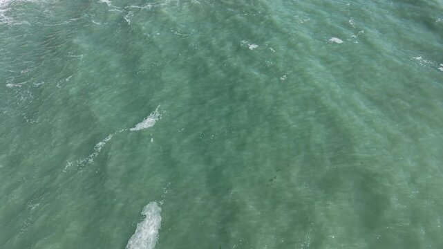 Top View Slow motion looping c ripples and wave, Refraction of sunlight top view texture sea side, Foaming and Splashing in the Ocean, Sunny Day, Slow Motion. Halkidiki, Greece. Veiw from drone