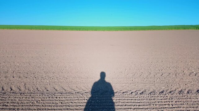 Shadow of a person over freshly plowed field