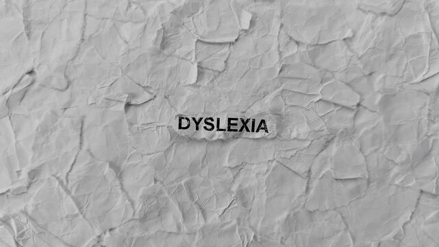 Crumpled piece of paper with word Dyslexia on torn crumpled white paper pieces background