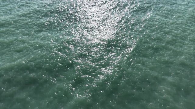 Top View Slow motion looping c ripples and wave, Refraction of sunlight top view texture sea side, Foaming and Splashing in the Ocean, Sunny Day, Slow Motion. Halkidiki, Greece. Veiw from drone