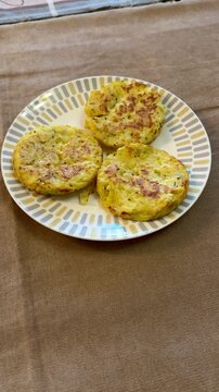 Three potato pancakes on plate, crispy golden draniki seasoned with pepper and herb flakes, served on patterned ceramic plate