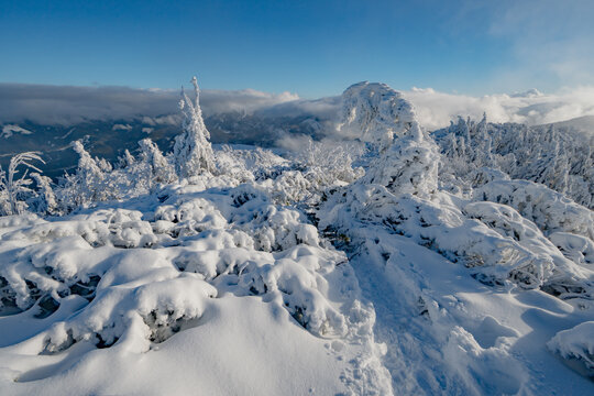 View of the snow-covered Salatin peak with frozen trees and a distant mountain range under a blue sky in Liptovska Stiavnica, Zilinsky kraj, Slovakia.