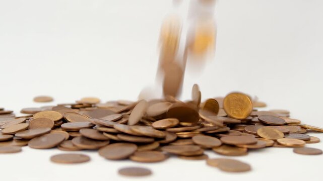 Bronze coins fall and bounce on flat white surface, scattering in close-up view