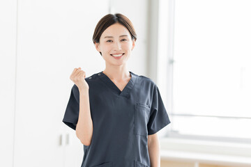 Fototapeta na wymiar ガッツポーズをしているスクラブを着た笑顔の日本人女性