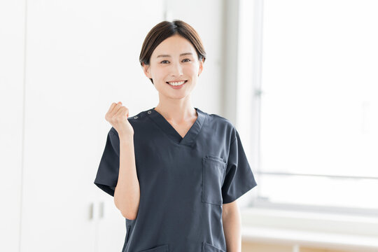 ガッツポーズをしているスクラブを着た笑顔の日本人女性