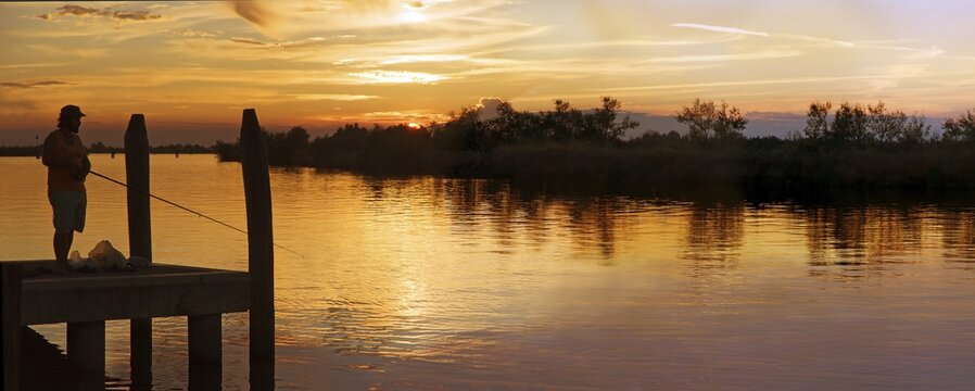Angler at sunset in Cavallino Harbour, view of lagoon, Venice, Italy
