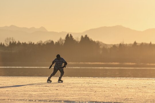 Ice skater, ice skating, man on frozen lake, evening light, backlight, mountains, Lake Starnberg, Alpine foothills, Bavaria, Germany