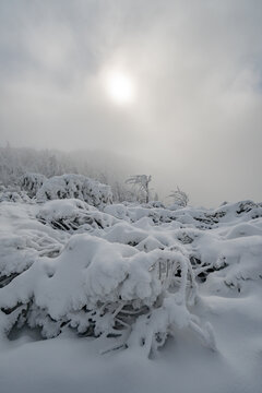 View of Salatin mountain peak covered in deep snow and frost under a misty sky with the sun breaking through in Liptovska Stiavnica, Zilinsky kraj, Slovakia.