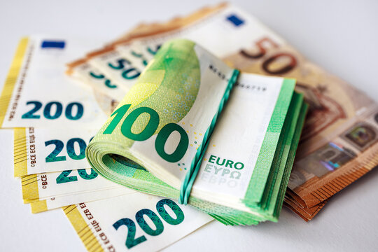 Close-up of a stack of euro banknotes with a rolled 100 euro bill placed on neatly arranged various euro currency notes on a flat surface. Concept finance, savings and money management.
