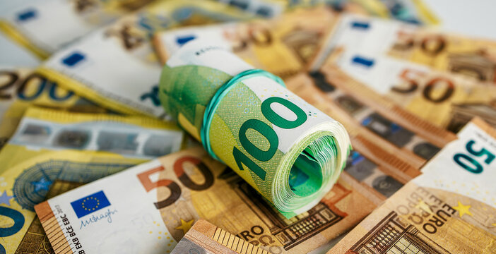Close-up euro financial scene with bundled 100 euro notes on scattered currency surface. Concept savings and economy.
