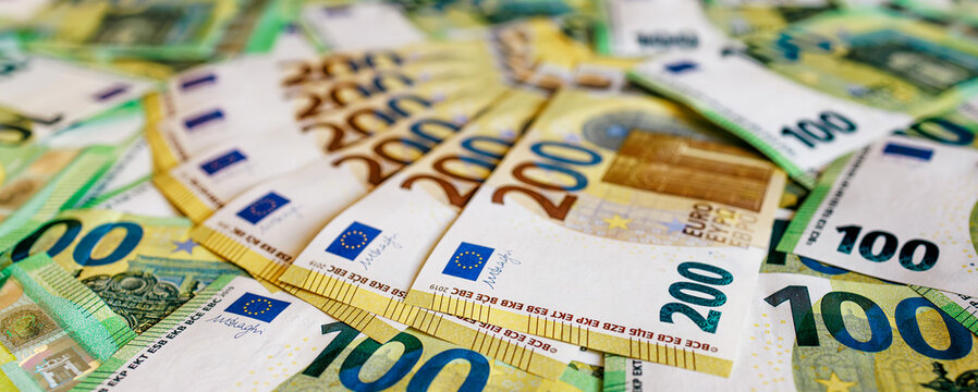 Close-up of euro banknotes of different denominations, including 100 and 200 euro notes, arranged on a flat surface. Concept finance, savings and economy.
