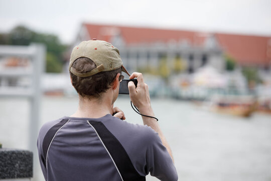 Man using digital camera to take travel photo, travel lifestyle and digital behavior, rear view.