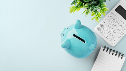 Obraz premium Top view of blue piggy bank with calculator and spiral notebook on blue background, finance planning, personal savings, and budgeting