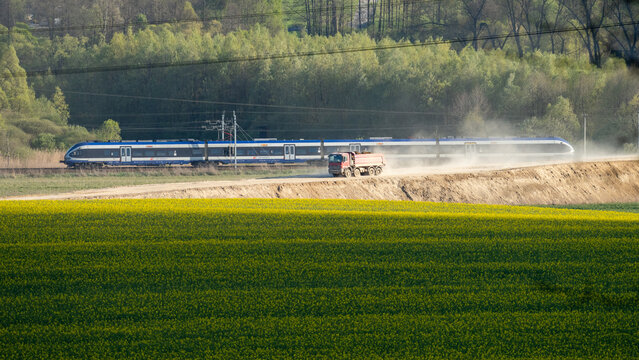 a truck working on the construction site of the Zabierz&oacute;w bypass, with a train passing in the background