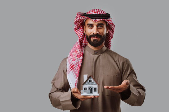 Arab man holding house model symbolizing real estate investment