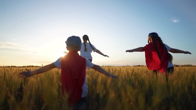 Superhero running through the wheat with his family. Child group superhero family concept. group of children are running together in a field. fun Superheroes run field of wheat children together.
