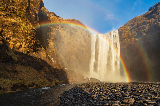 Skagafoss waterfall, cliffs and a Double Rainbow, a cascade falling into a pool.