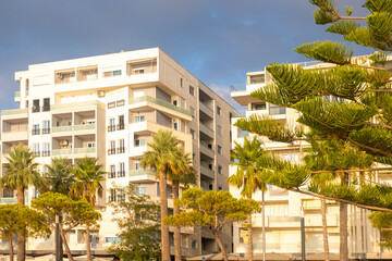 Contemporary Modern residential buildings facade with balconies under clear blue sky, community with lush greenery, modern architecture_ well-maintained landscape, apartment buildings city lifestyle © kittyfly