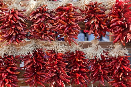 Decorative arrangements of dried chili peppers, called ristras, hanging up for sale