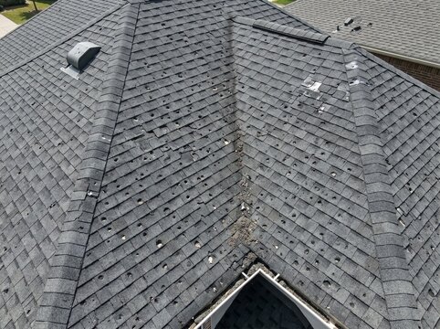 Severe hail damage on asphalt shingle roof after storm