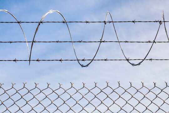 Chain link fence topped with barbed and razor wire