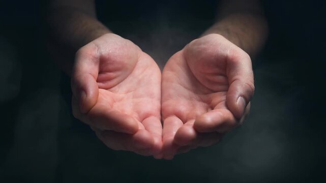 Open human hands cupped together with a dark smoky background for giving and receiving concept