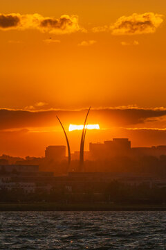 View of the Air Force Memorial spires silhouetted against a vibrant orange sunset over the Potomac River and city skyline in Washington, District of Columbia, United States.