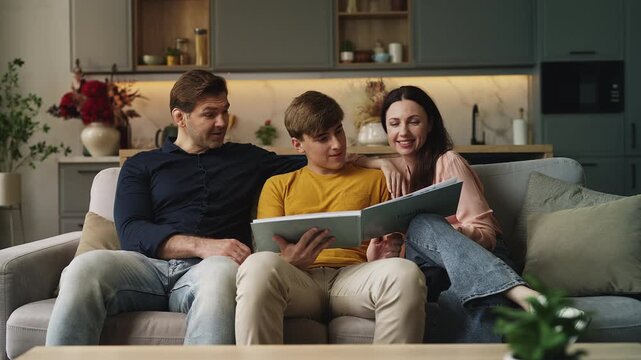Parents and teen son looking through a family photo album, sharing memories