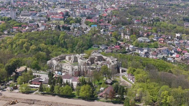 Drone view of Suceava Fortress surrounded by greenery and cityscape in Suceava, Romania