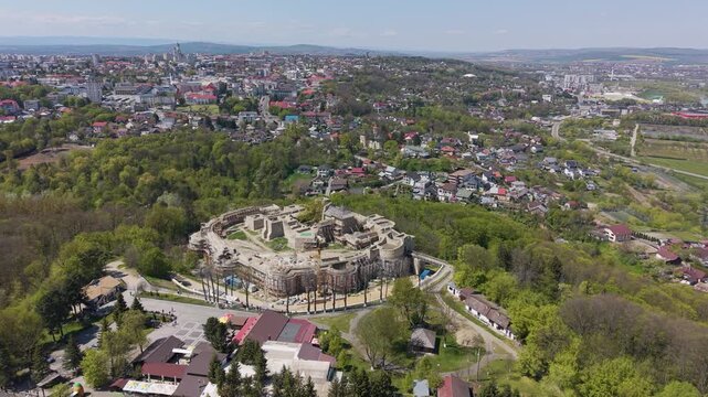 Cinematic drone orbit around Suceava Fortress with panoramic cityscape and green hills in Suceava, Romania