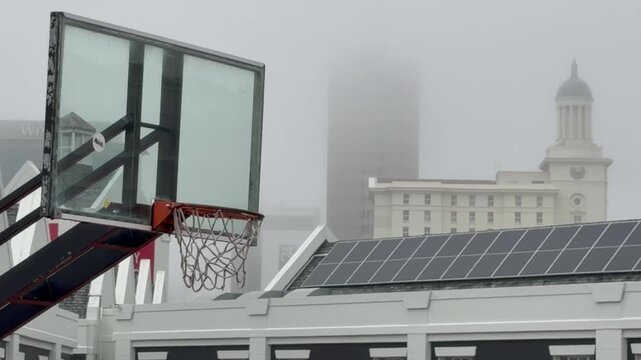 A basketball hoop in a city on a misty day.