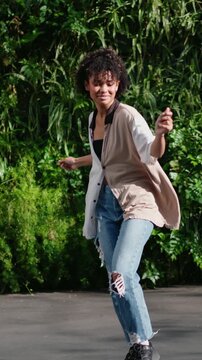 young woman lets her body move freely, embracing joy of dance in outdoor setting filled with lush greenery.moment of pure, carefree happiness.beauty of spontaneous dance and freedom of self-expression