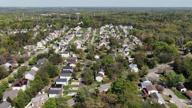 American suburb neighborhood with row homes in classical and colonial style during sunny spring day. Aerial flyover shot. Green trees and grass in yards in April. Charming small town vibes in USA.